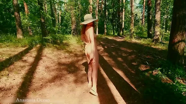 A nudist girl walks in forest near the beach among dressed people. (Emerald Ocean)